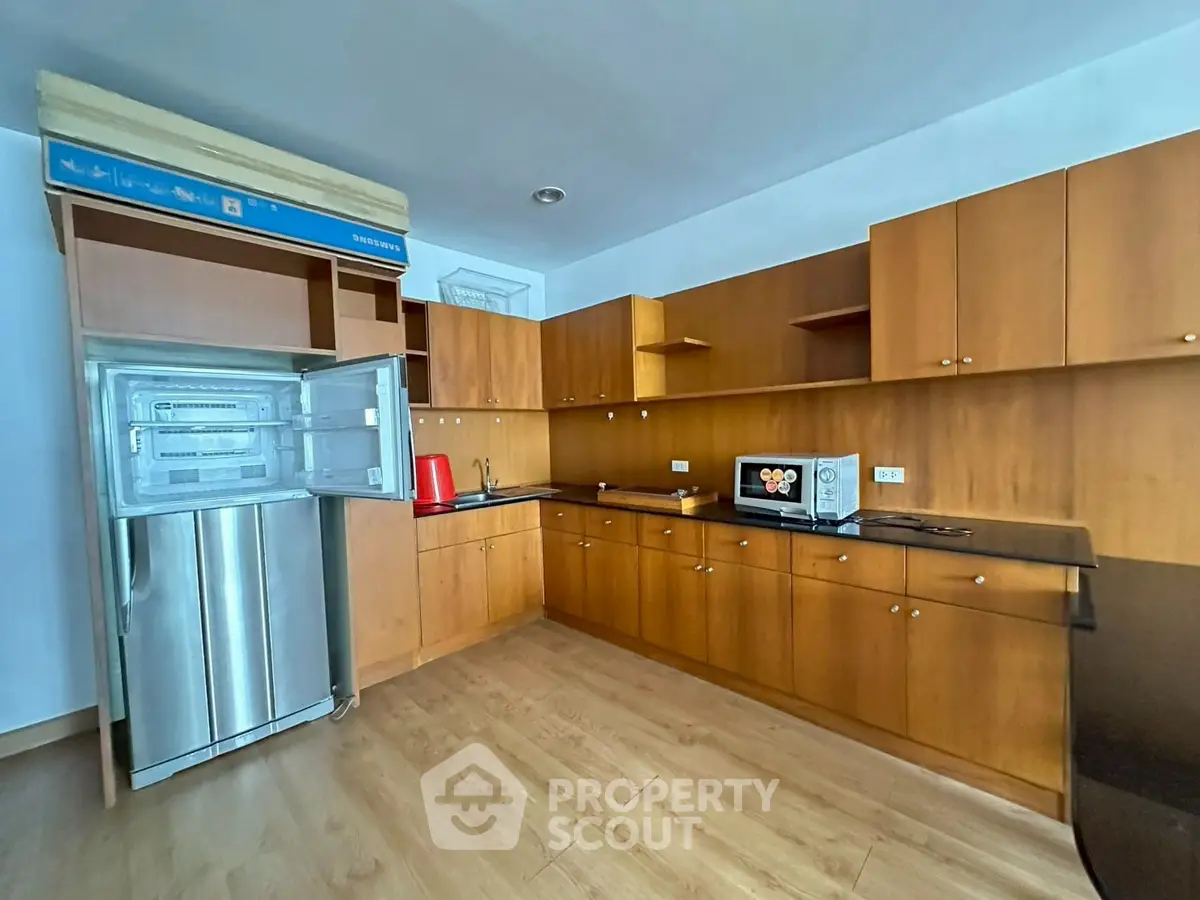 Spacious kitchen with wooden cabinets and modern appliances in a bright apartment.