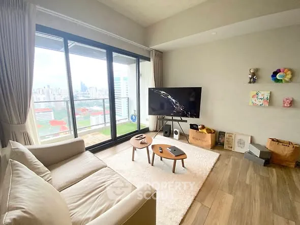 Modern living room with large windows and city view, featuring cozy seating and stylish decor.