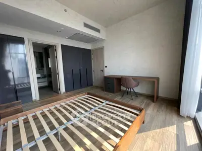 Spacious bedroom with wooden flooring and modern furniture, featuring a large window for natural light.