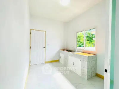 Bright minimalist kitchen with white cabinets and large window view