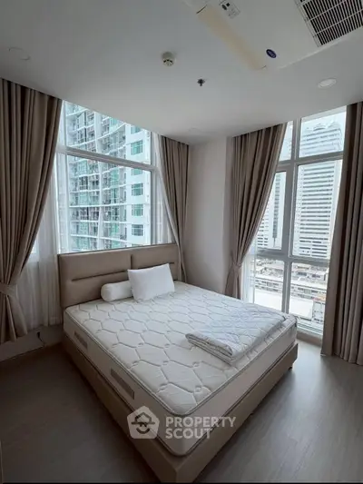Modern bedroom with large windows offering stunning city views in a high-rise apartment.