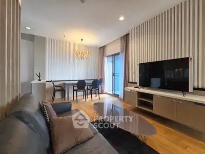 Modern living room with stylish decor and open dining area, featuring a sleek TV setup and elegant lighting.