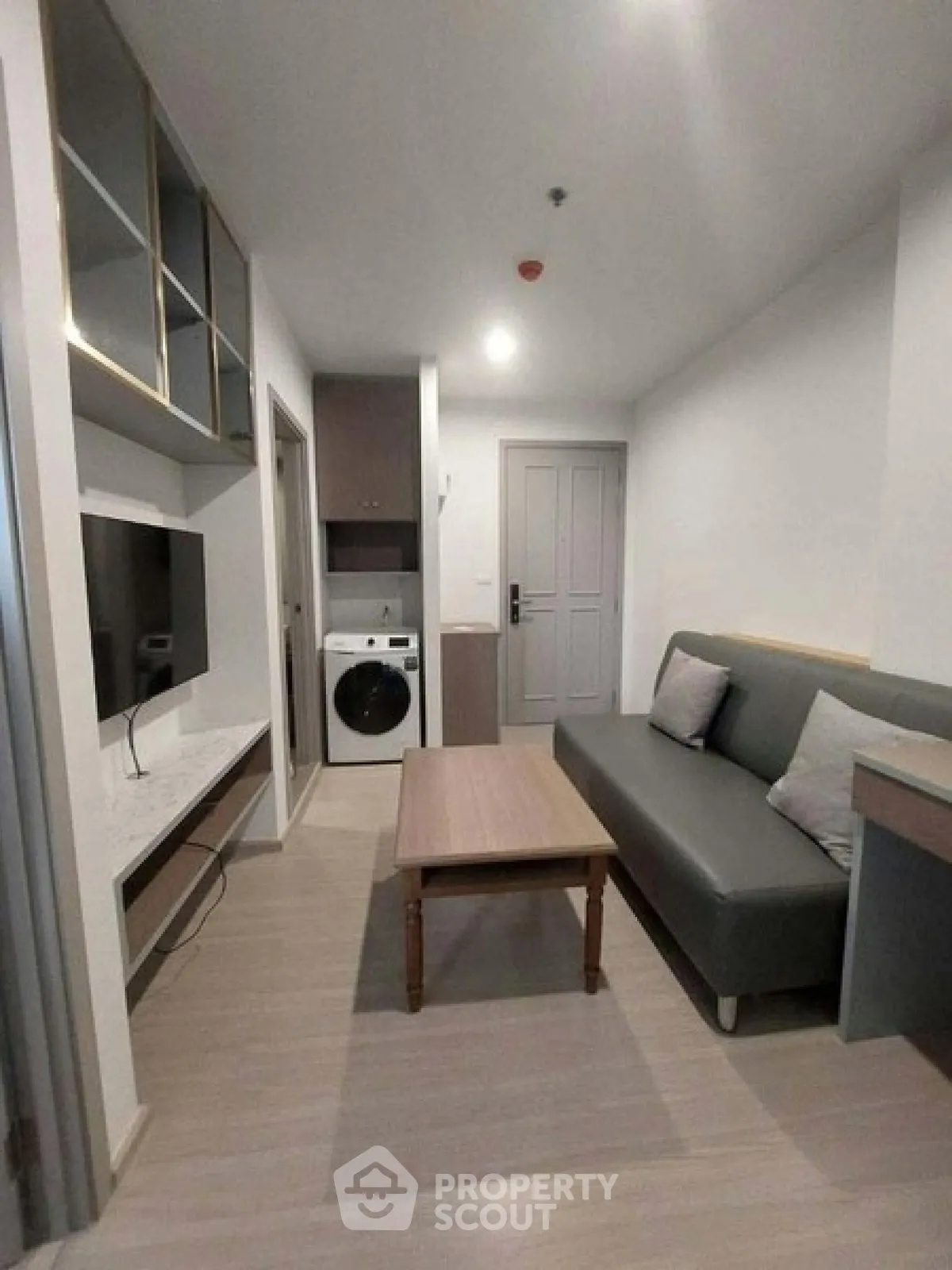 Modern living room with sleek furniture and built-in TV unit in a cozy apartment.