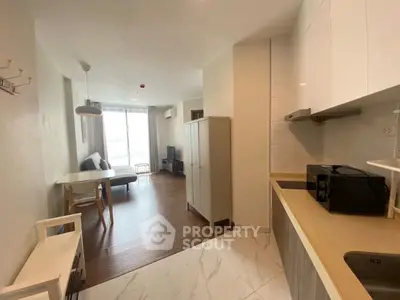 Modern open-plan living room with kitchen, featuring sleek furniture and natural light.