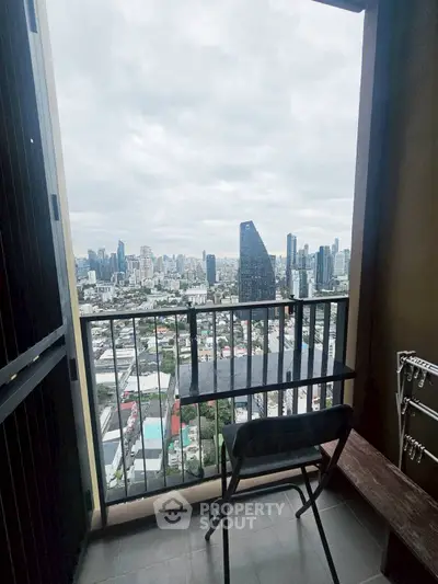 Stunning cityscape view from a high-rise balcony with modern chair and railing.