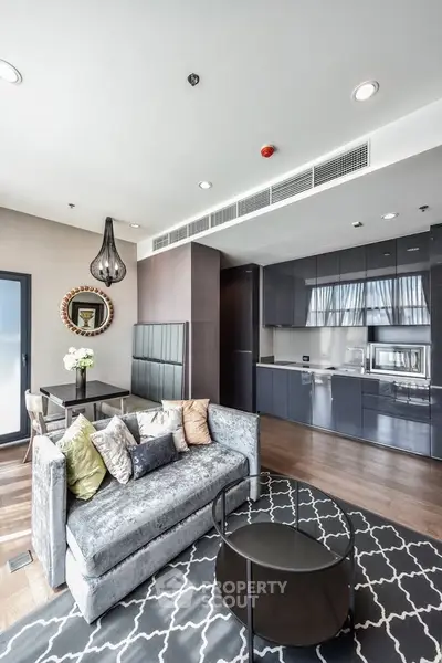Modern living room with open kitchen, stylish decor, and natural light.