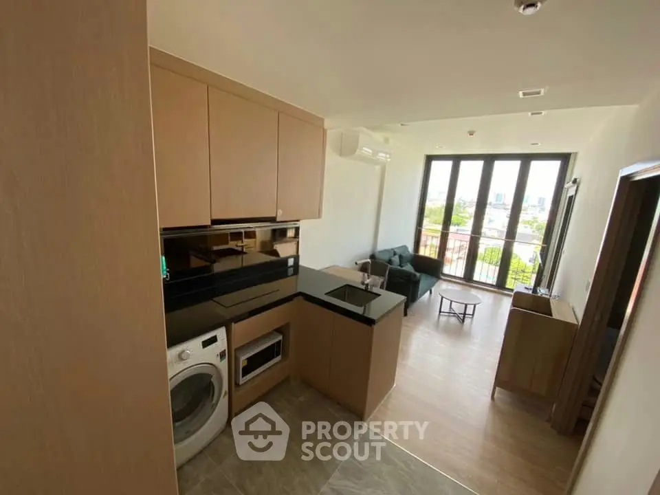 Modern open-plan living room with kitchen and balcony view in a stylish apartment.