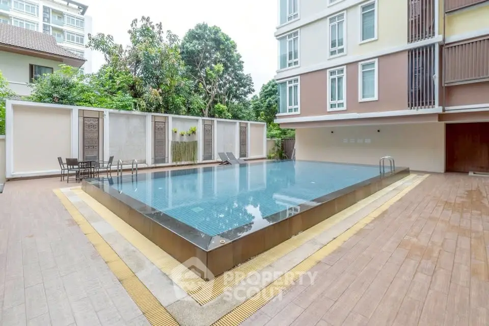 Luxurious apartment complex with modern pool and stylish outdoor seating area.