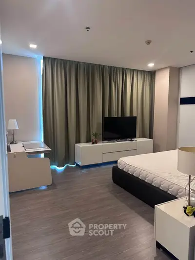 Modern bedroom with sleek furniture and large TV, perfect for urban living.