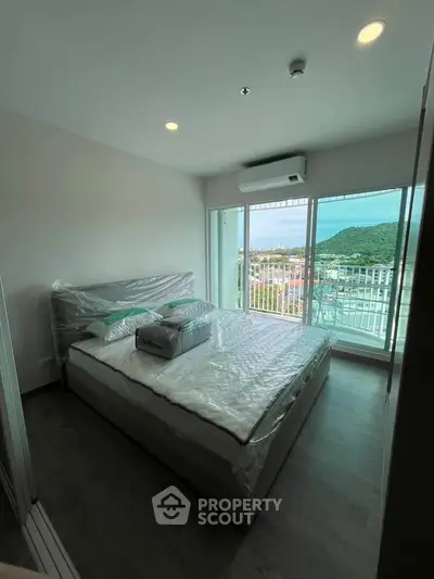 Modern bedroom with large windows and scenic view of hills and water.