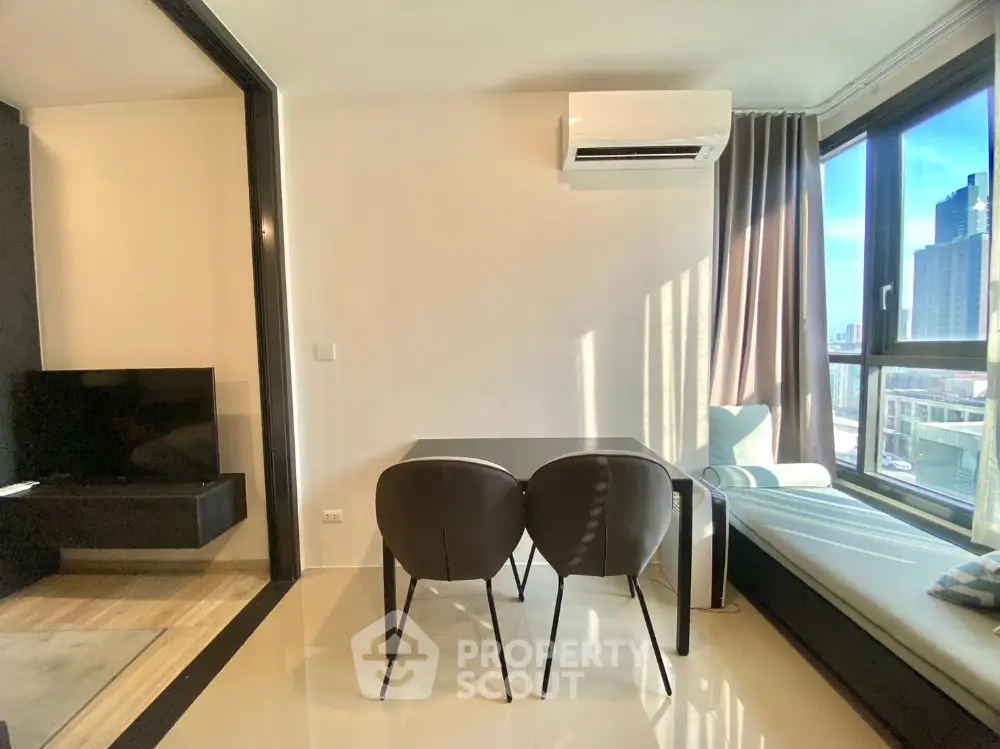 Modern apartment interior with dining area and city view, featuring sleek furniture and natural light.