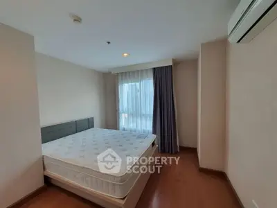 Spacious bedroom with large window and air conditioning in modern apartment.