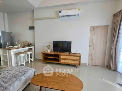 Modern living room with sleek furniture and air conditioning, featuring a cozy TV area and stylish decor.