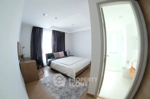 Spacious bedroom with modern decor and ensuite bathroom, featuring large windows and elegant furnishings.
