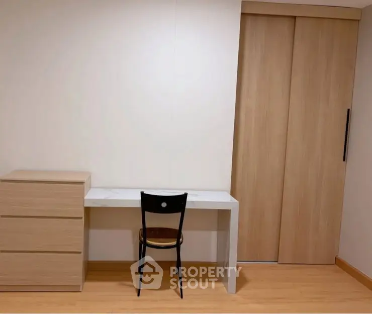 Minimalist study area with desk, chair, and wooden storage in modern apartment.