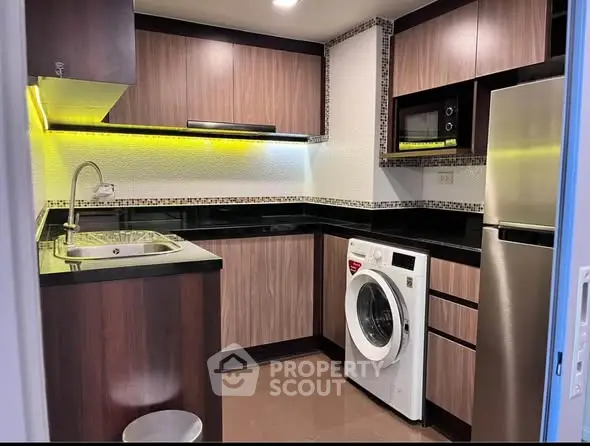 Modern kitchen with sleek cabinets, washing machine, and stainless steel appliances.