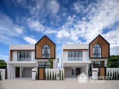 Modern twin houses with sleek design and large windows under a vibrant blue sky.