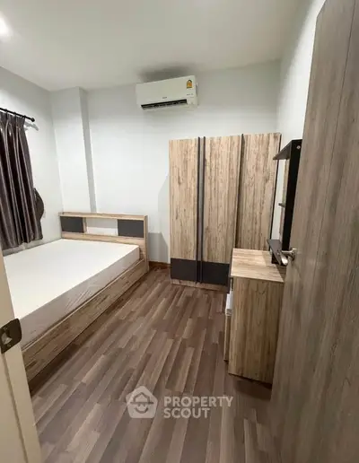 Modern bedroom with wooden furniture and air conditioning in a cozy apartment.