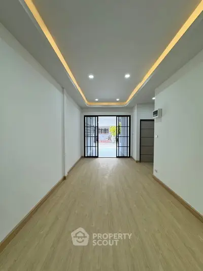 Spacious modern interior with wooden flooring and recessed lighting, ideal for versatile living space.