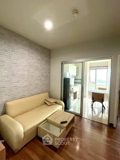 Modern living room with beige sofa and sliding glass doors leading to a bright kitchen area.