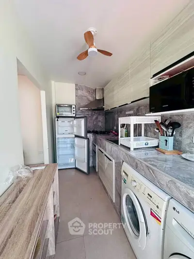 Modern kitchen with appliances and sleek design, featuring washing machine and open layout.