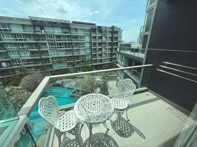 Modern balcony with stylish furniture overlooking pool and contemporary buildings