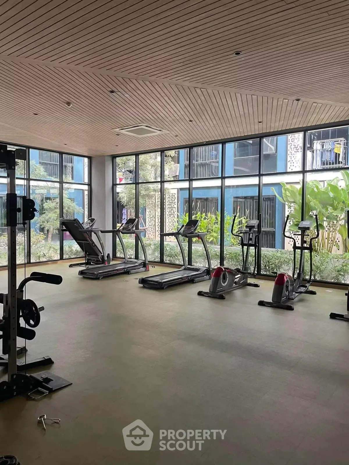 Modern gym with large windows and fitness equipment in a stylish residential building.