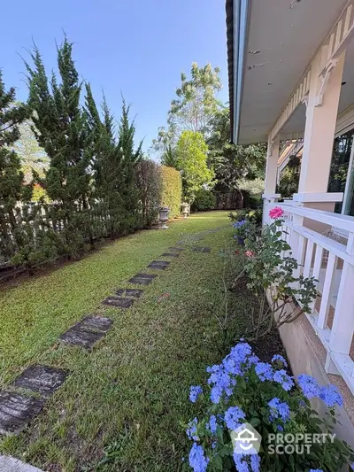 Charming garden view with lush greenery and vibrant flowers next to a cozy home exterior.