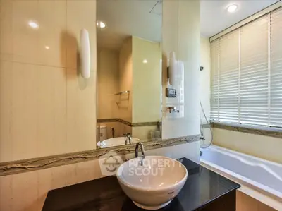 Luxurious bathroom with modern sink and bathtub, elegant design and ample natural light.