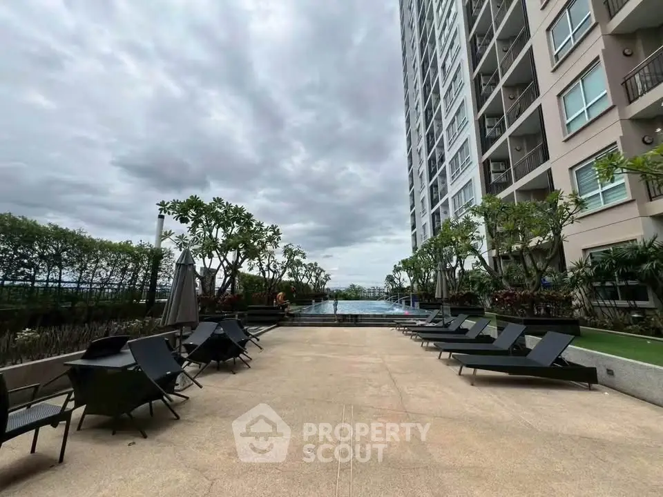 Luxurious high-rise building with poolside lounge area and lush greenery.