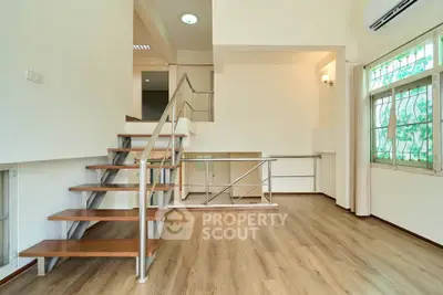 Spacious modern living room with wooden flooring and stylish staircase, perfect for contemporary living.