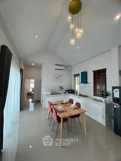 Modern open-layout kitchen and dining area with high ceiling and stylish lighting.