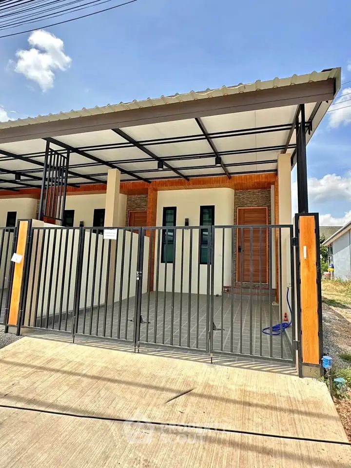 Modern single-story house with gated entrance and covered carport under a clear blue sky.