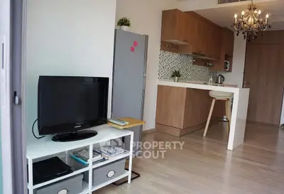 Modern open-layout kitchen and living area with stylish chandelier and sleek appliances.