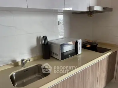 Modern kitchen with sleek countertop, microwave, and induction cooktop.