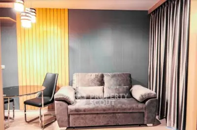 Modern living room with stylish sofa and dining area, featuring elegant lighting and contemporary decor.