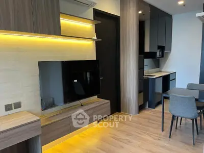 Modern open-layout living room with sleek kitchen and dining area, featuring wood flooring and ambient lighting.