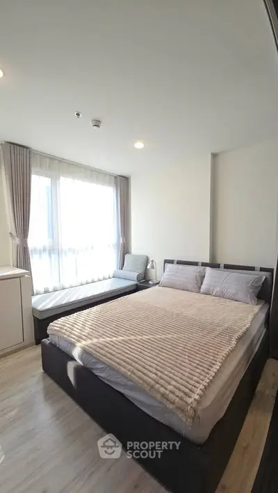 Spacious bedroom with large windows and modern furnishings in a stylish apartment.