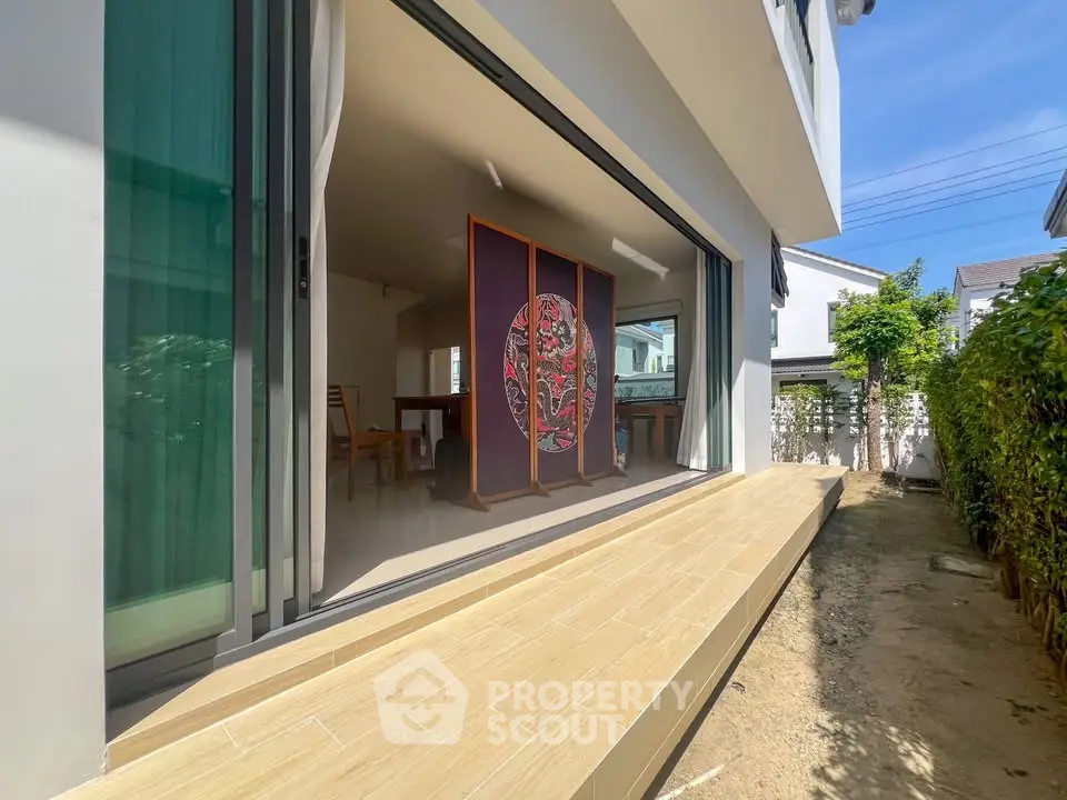 Modern home with open sliding doors leading to a serene garden, showcasing seamless indoor-outdoor living.