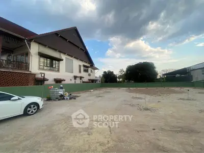 Spacious residential plot with adjacent house and clear sky view, ideal for development opportunities.