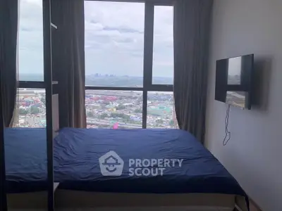 Modern bedroom with large window offering stunning city view, featuring wall-mounted TV and cozy bed.