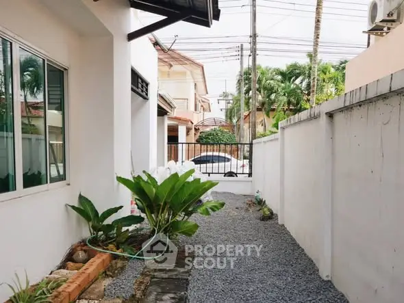 Charming exterior view of a residential property with lush greenery and gravel pathway.
