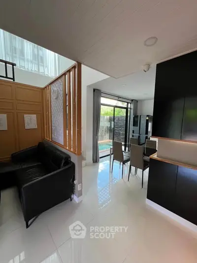 Modern open-plan living and dining area with sleek black furniture and large windows for natural light.