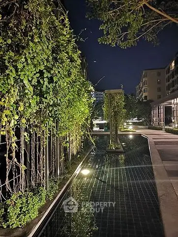 Luxurious night view of modern building with serene water feature and lush greenery