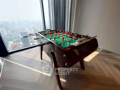 Luxurious high-rise apartment with stunning city view and stylish foosball table in living area.