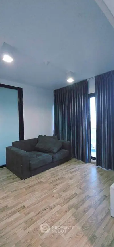 Spacious living room with modern sofa and large window offering natural light.