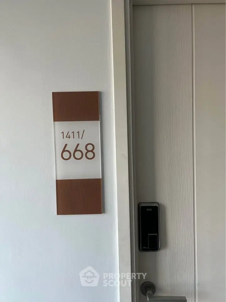 Modern apartment door with electronic lock and unit number 1411/668, showcasing secure urban living.