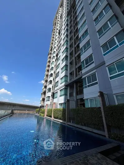 Modern high-rise building with a luxurious pool and clear blue sky.