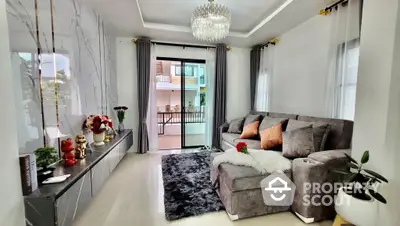 Luxurious living room with elegant chandelier, plush sofa, and balcony access, showcasing modern design and comfort in a high-end property.