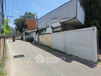 Quiet residential street with detached houses and lush greenery.